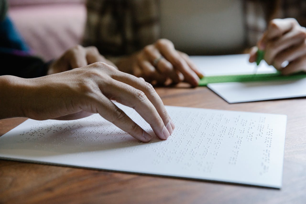 Hands feel Braille text on paper, demonstrating tactile reading and sensory education.